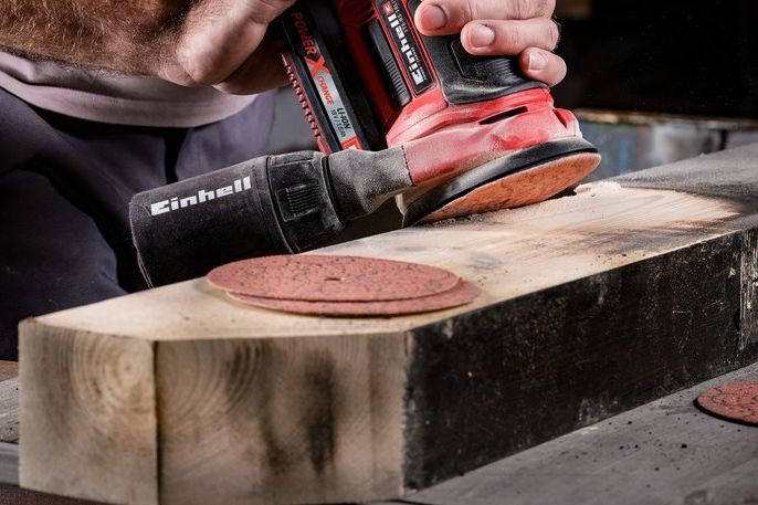 Person schleift Holz mit einem Schwingschleifer